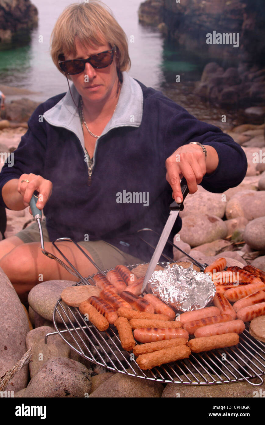 Frau grillen Würstchen am Strand Stockfoto