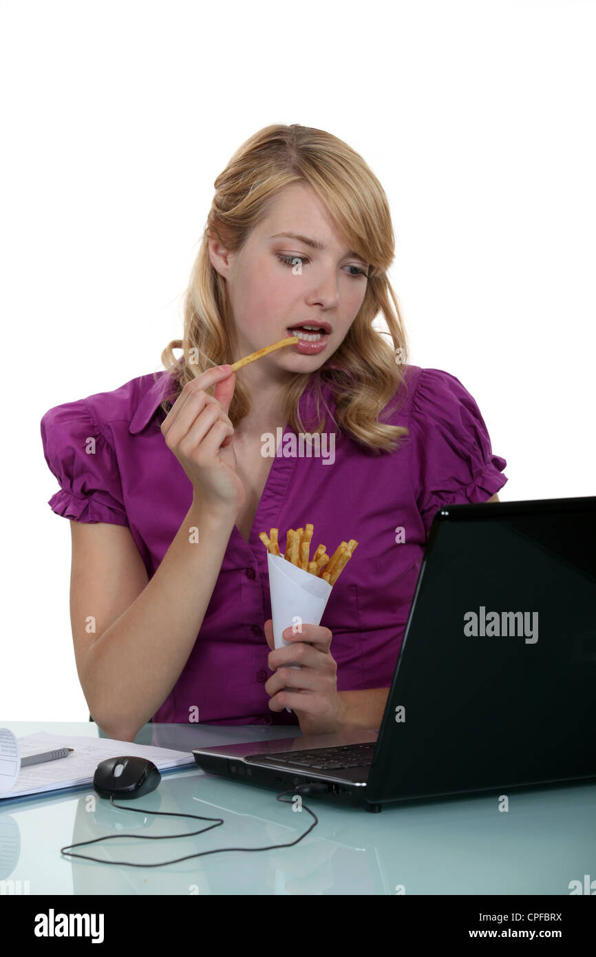 Frau Schreiber essen Pommes frites an ihrem Schreibtisch Stockfoto