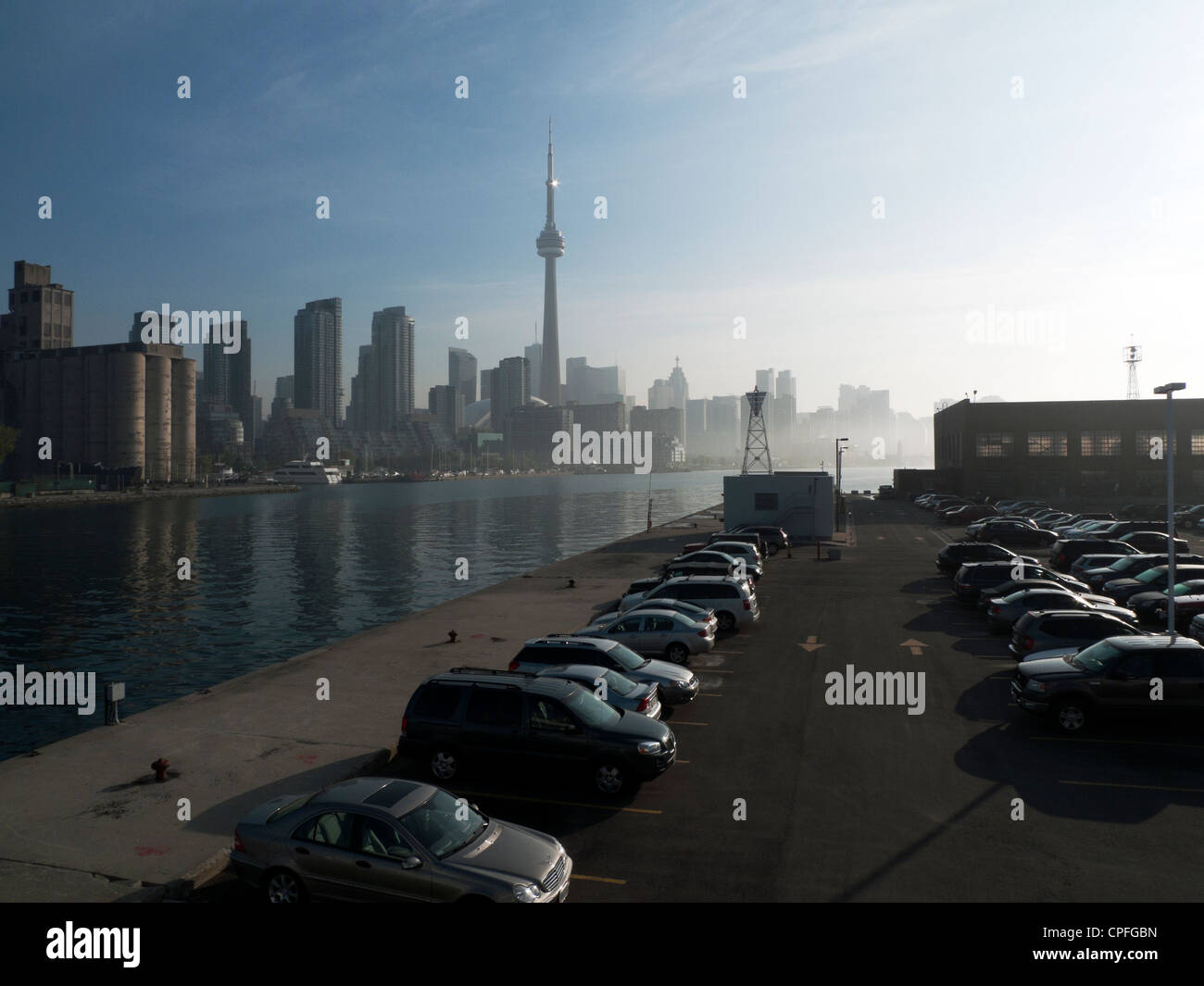 Autos parkten auf dem Fährenparkplatz zum Billy Bishop Toronto City Airport und nebliger Blick am frühen Morgen auf den CN Tower von der Toronto Island in Ontario, Kanada Stockfoto