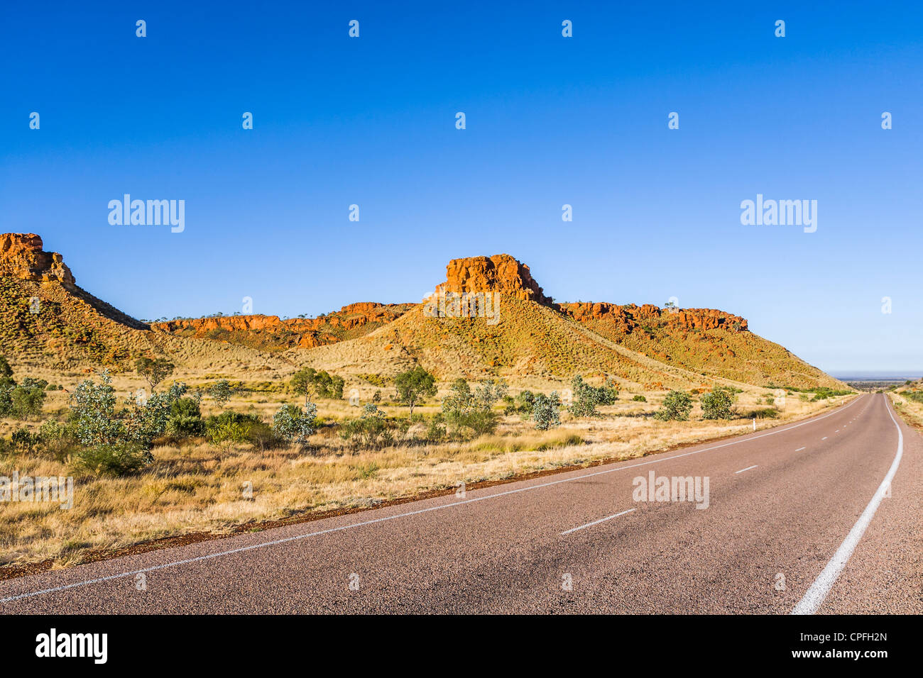 Lange Straße in der Kimberley Region von Westaustralien Curvinga um einen roten Felsen Mesa. Dies ist Ngumpan Cliffs. Stockfoto