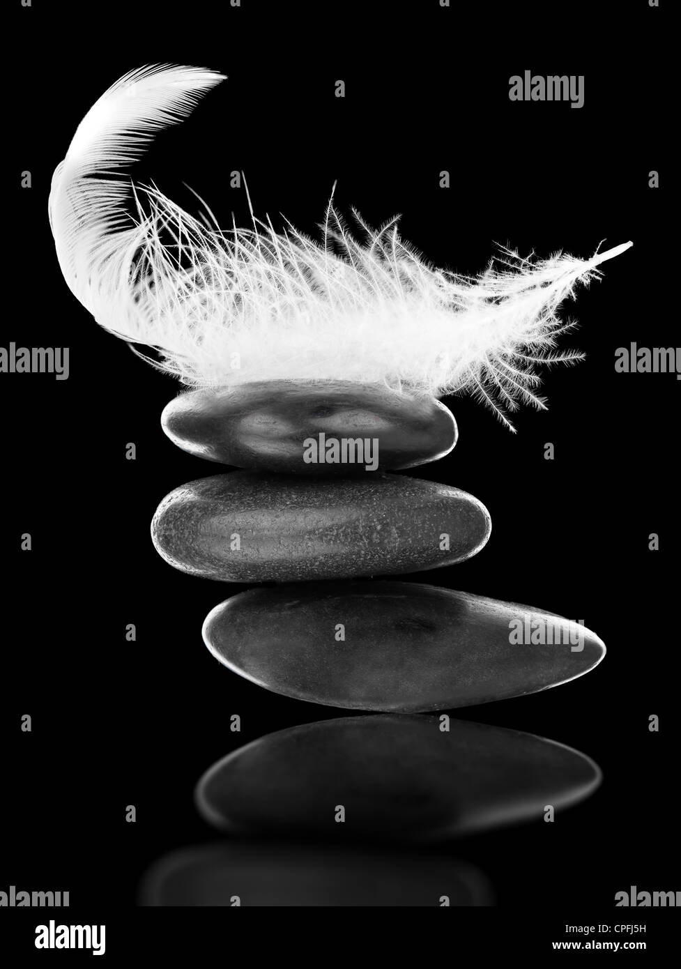 Weiße Feder auf Stapel von schwarzen Kieseln auf schwarzem Hintergrund - Gleichgewicht, Stabilität und Gleichgewicht-Konzept Stockfoto