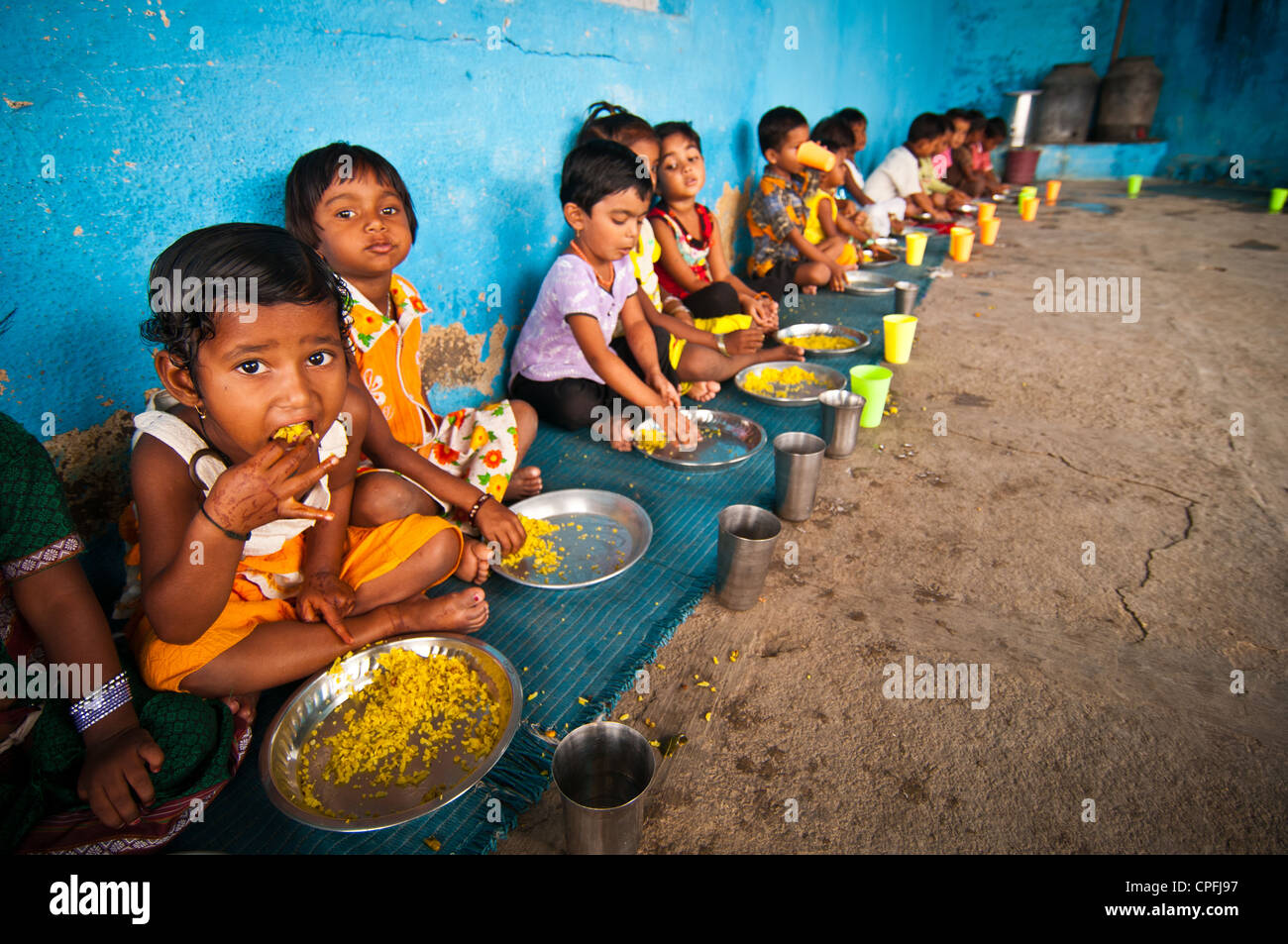 Indische Kinder sitzen auf dem Boden essen in der Schule. Stockfoto