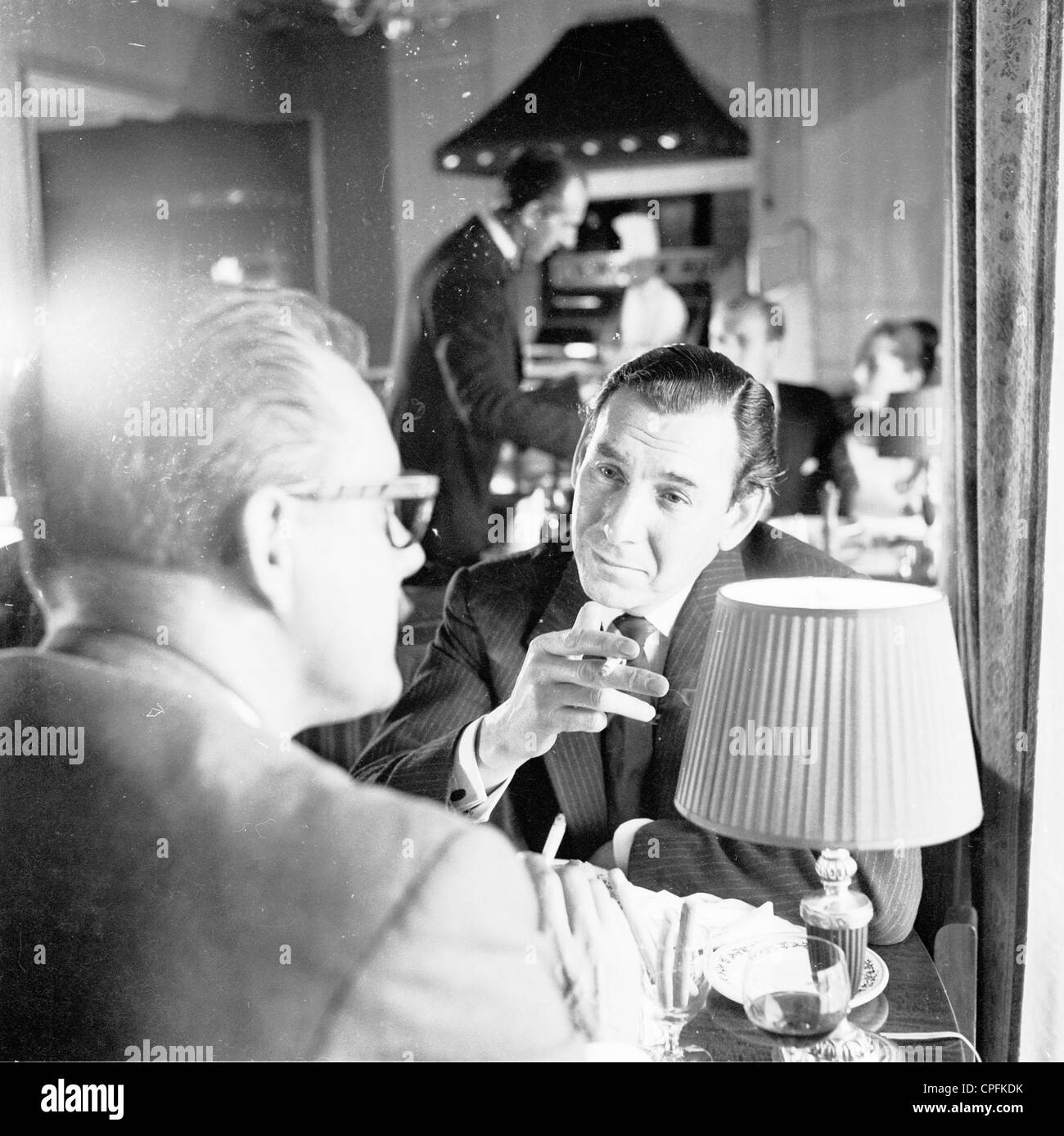 Bild aus der 1960er Jahre. Ein Mann in einem Restaurant mit einer Zigarette mit seiner Mahlzeit. Sein Begleiter ist auch das Rauchen. Stockfoto