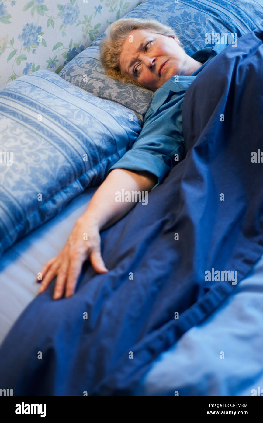 Reife Frau im Bett liegt und auf den leeren Platz neben ihr Stockfoto