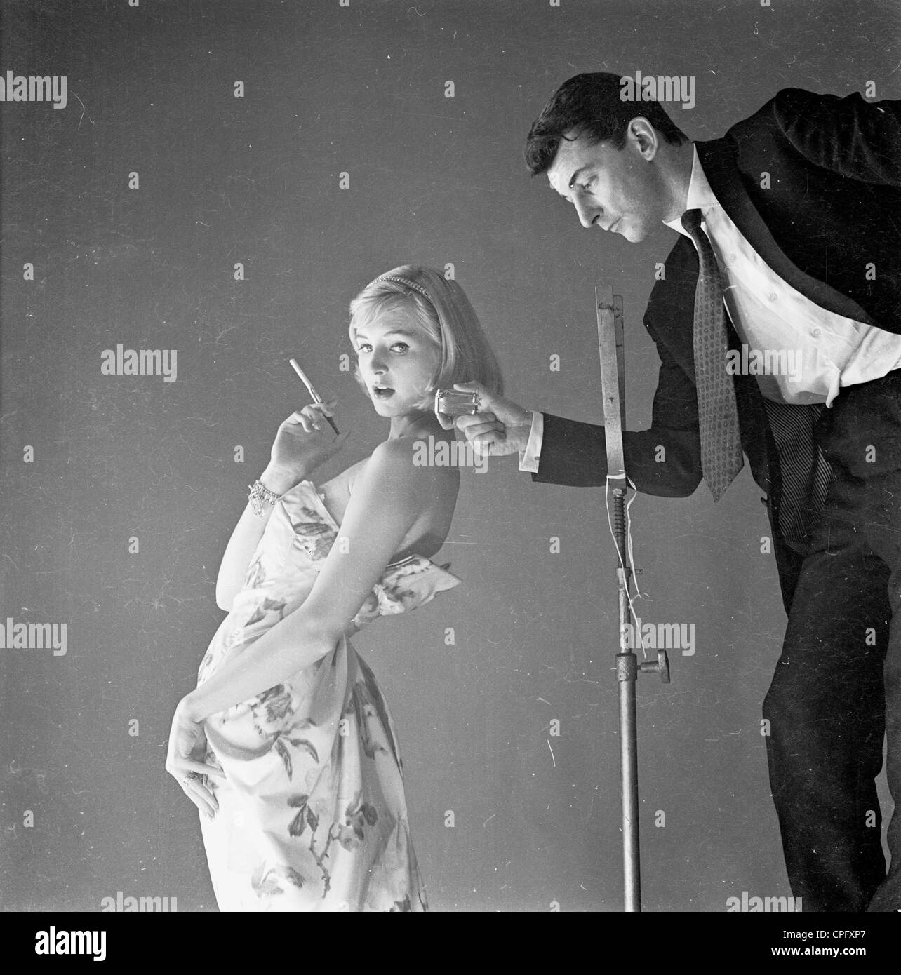 Adverting noch von sechziger Jahre Rauchen zu fördern. Studioumgebung wo ein geeignet Mann geht zu einer hübschen Dame Zigarette anzünden. Stockfoto