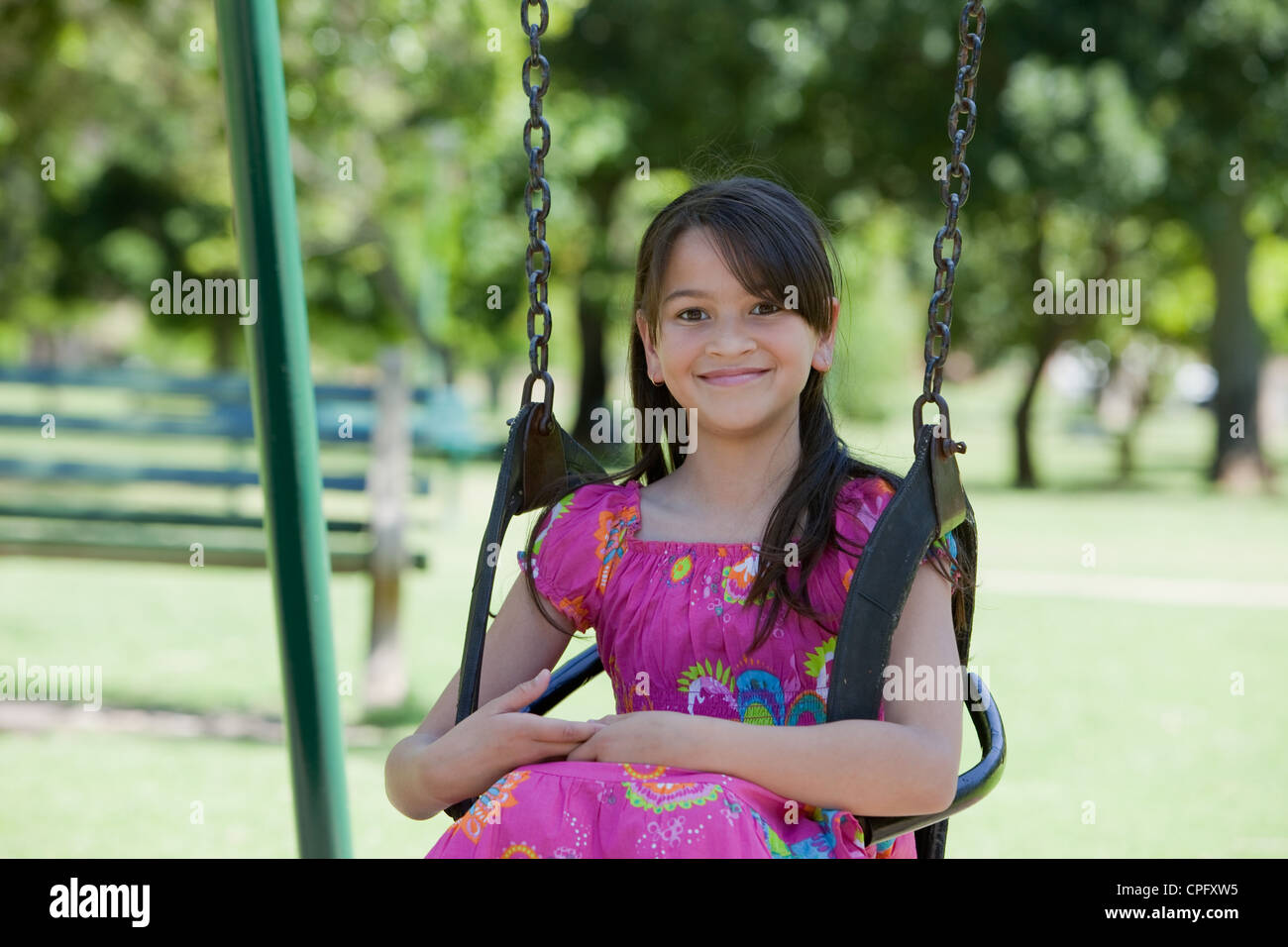 Porträt eines Mädchens sitzen auf einer Schaukel auf dem Spielplatz, lächelnd. Stockfoto