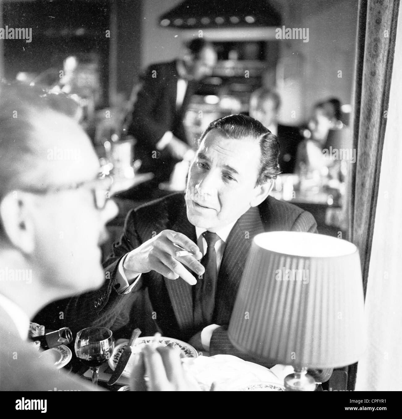 Es ist der 1960er Jahre und ein Geschäftsmann in einem Restaurant genießt eine Zigarette mit seine Mahlzeit. Stockfoto