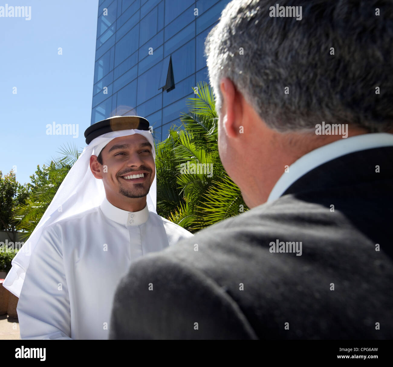Arabische Geschäftsmann und westliche Geschäftsmann vor Gebäude, lächelnd. Stockfoto