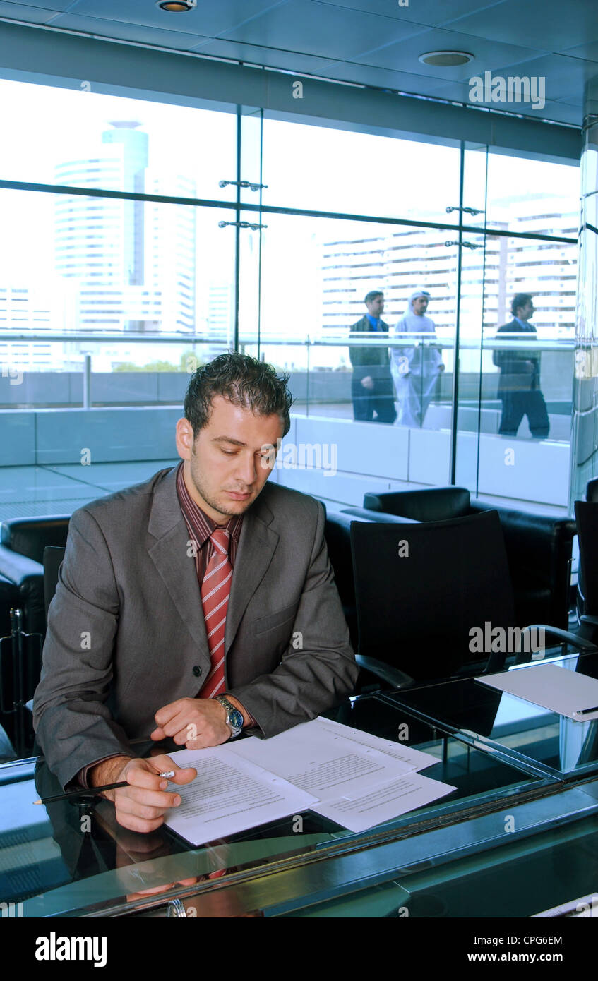 Ein Geschäftsmann mit Schwerpunkt auf seine Arbeit und seine Kolleginnen und Kollegen aus dem Hintergrund zu sehen. Stockfoto