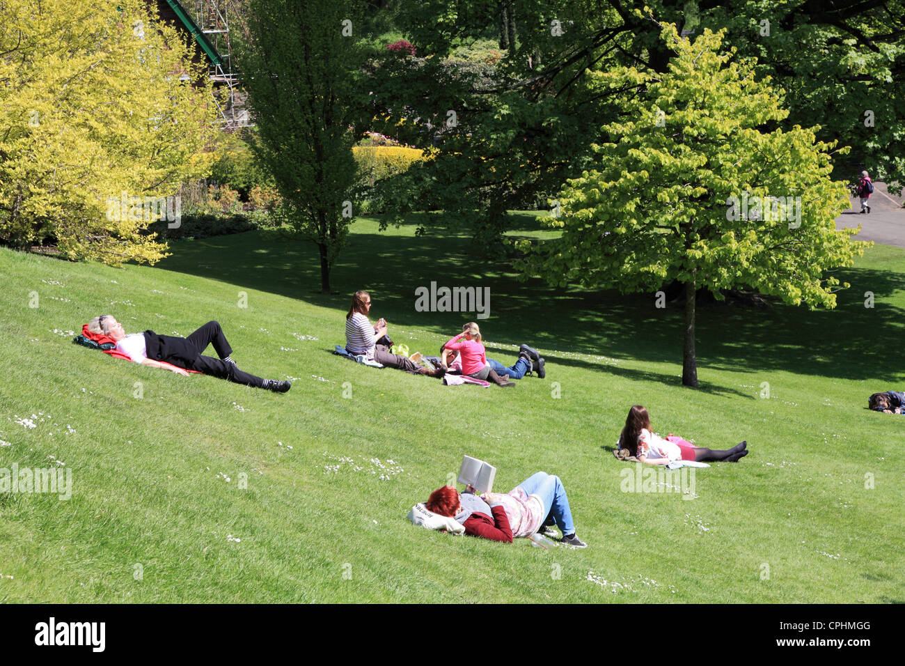 Junge Frauen auf der Wiese entspannen und genießen der Sonne Princes Street Gardens Edinburgh Schottland UK Stockfoto