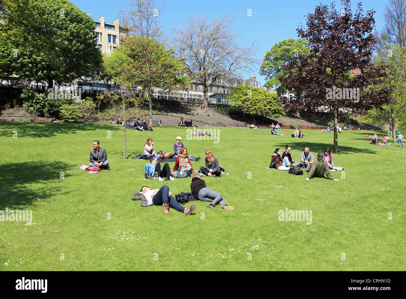 Junge Leute genießen den Sonnenschein in Princes Street Gardens, Edinburgh Scotland UK Stockfoto