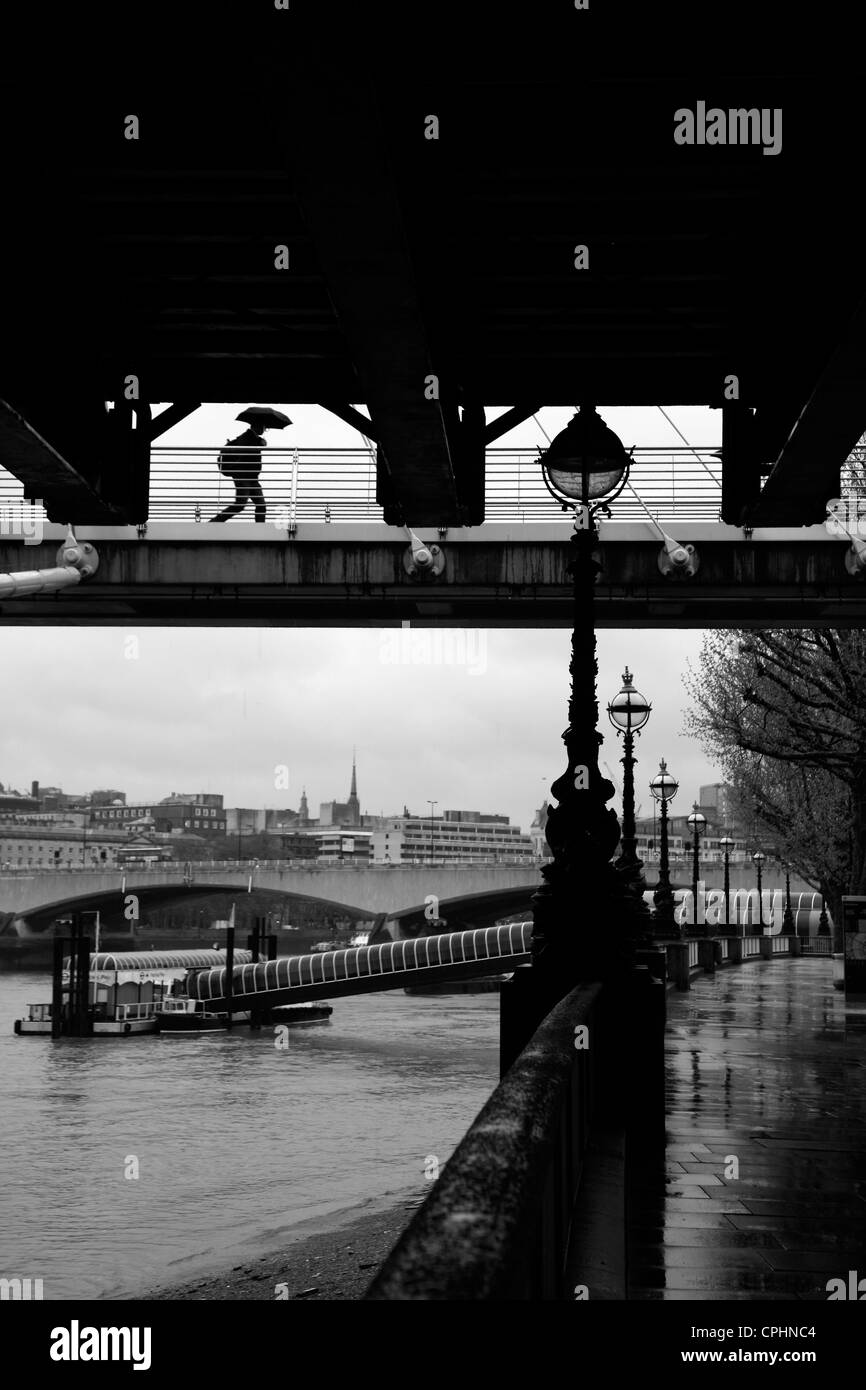 Regnerischen Blick auf die Königin zu Fuß genommen unter Hungerford Eisenbahnbrücke und goldenes Jubiläum Fußgängerbrücke, South Bank, London, UK Stockfoto