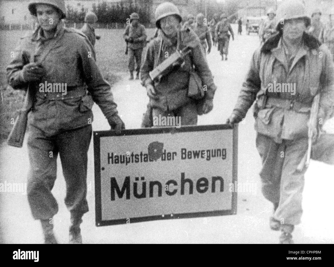 Amerikanische Soldaten marschieren in München tragen das Ortsschild (Überschrift "München - Hauptstadt der Bewegung"), München, 30. April 1945, Stockfoto