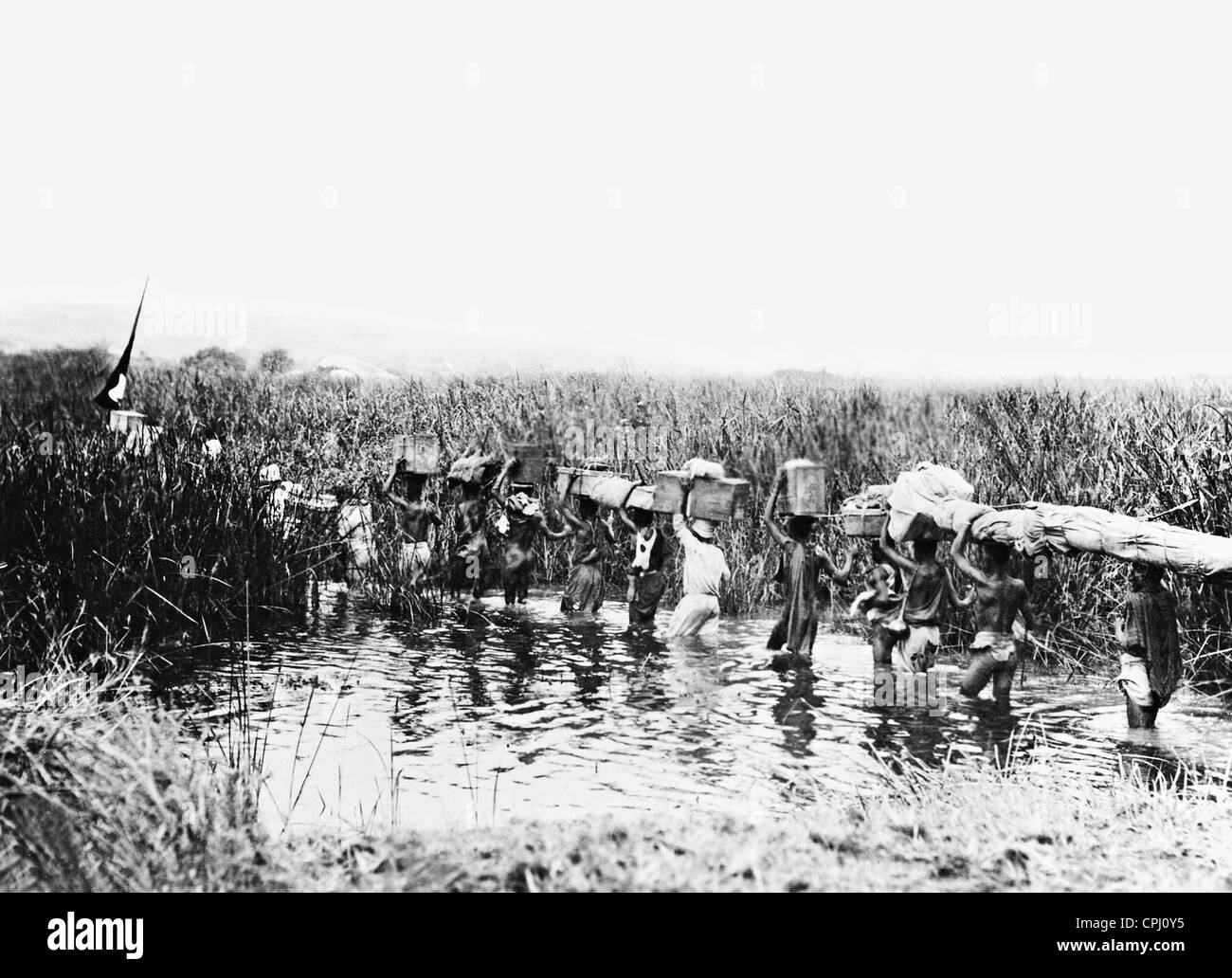 Konvoi von Trägern, die Überquerung eines Flusses, 1908 Stockfoto