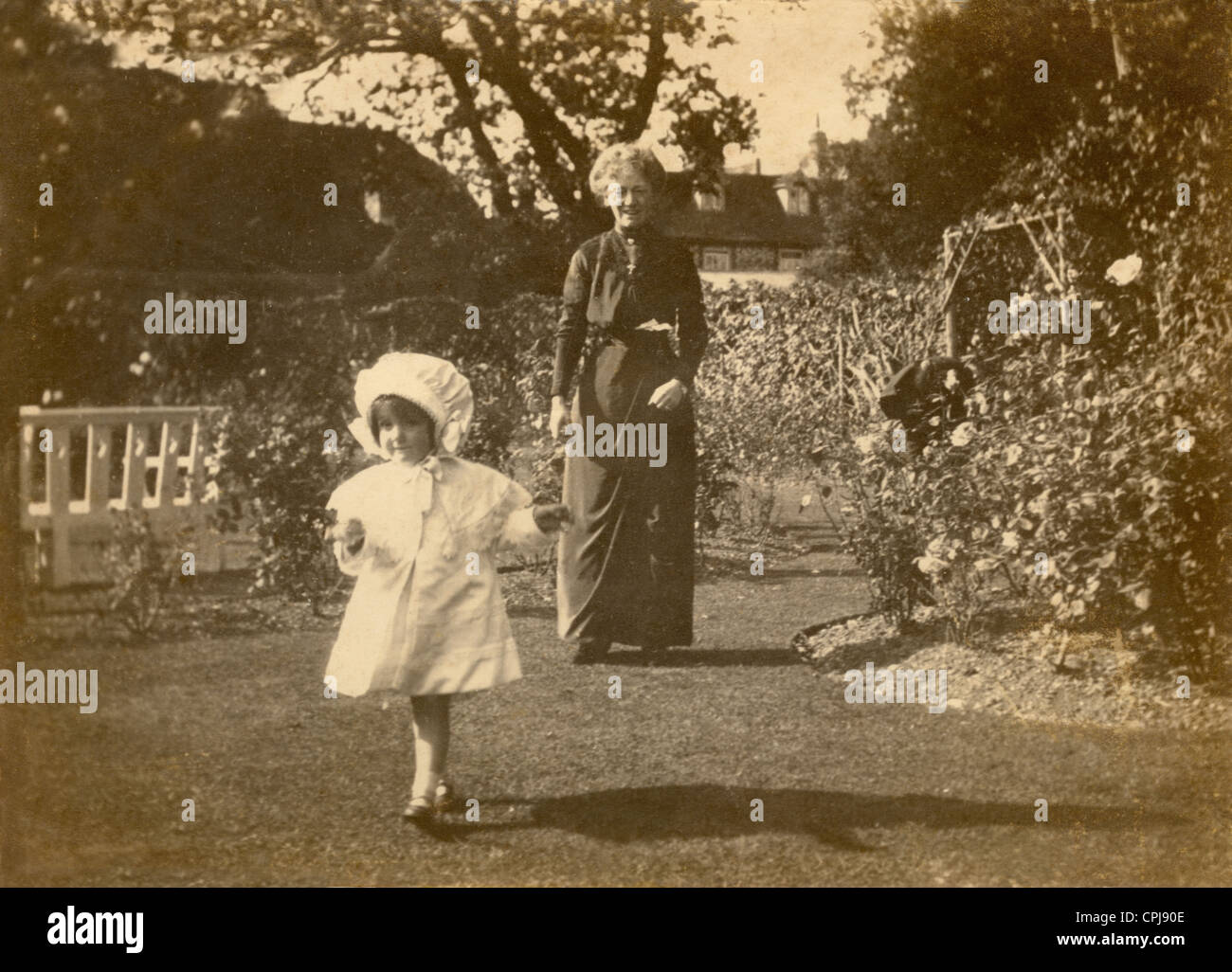 Original Edwardian Foto von Nursery Krankenschwester oder Großeltern mit Kind in einem Garten während der Edwardian Periode, Anfang 1900, Großbritannien. Stockfoto