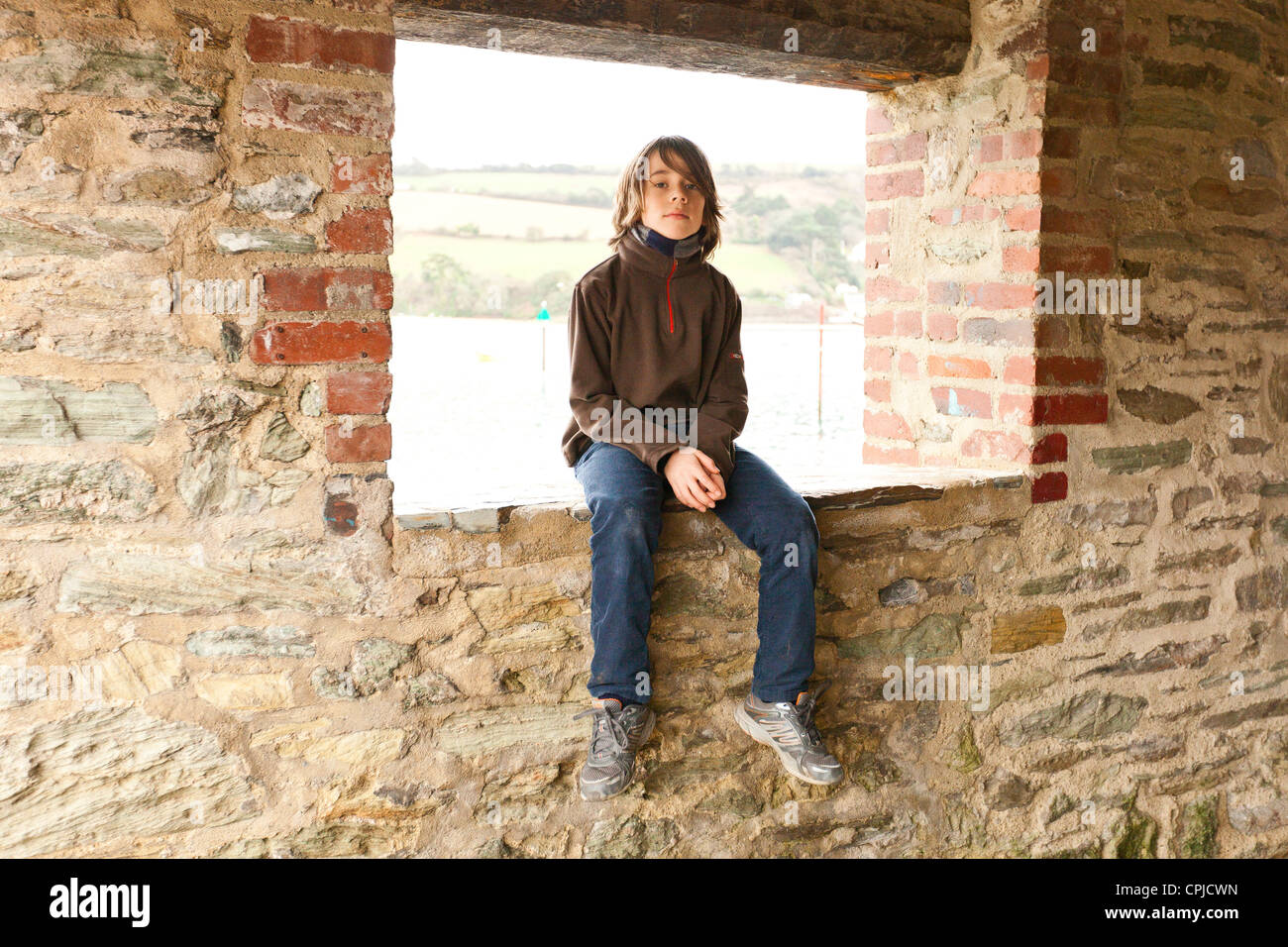 Junge sitzt auf der Mauer Stockfoto