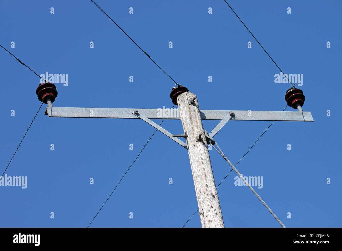 Telegrafenmast und Stromkabel gegen klar tiefblauen Himmel Stockfoto
