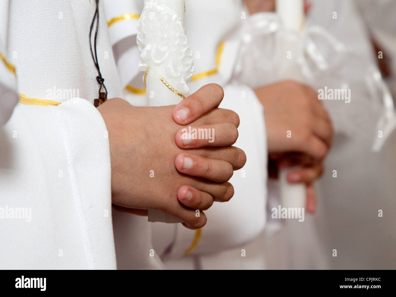 Hände von Kindern durch Erstkommunion mit den Kerzen Stockfoto