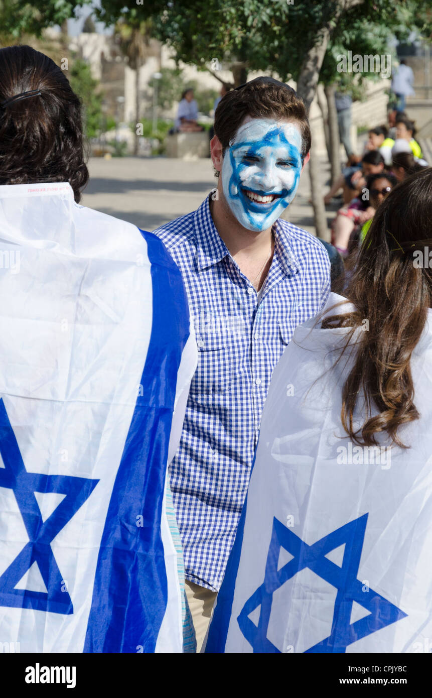 Junger Mann mit einer israelischen Flagge gemalt auf seinem Gesicht mit Menschen anhalten. Jerusalem. Israel. Stockfoto
