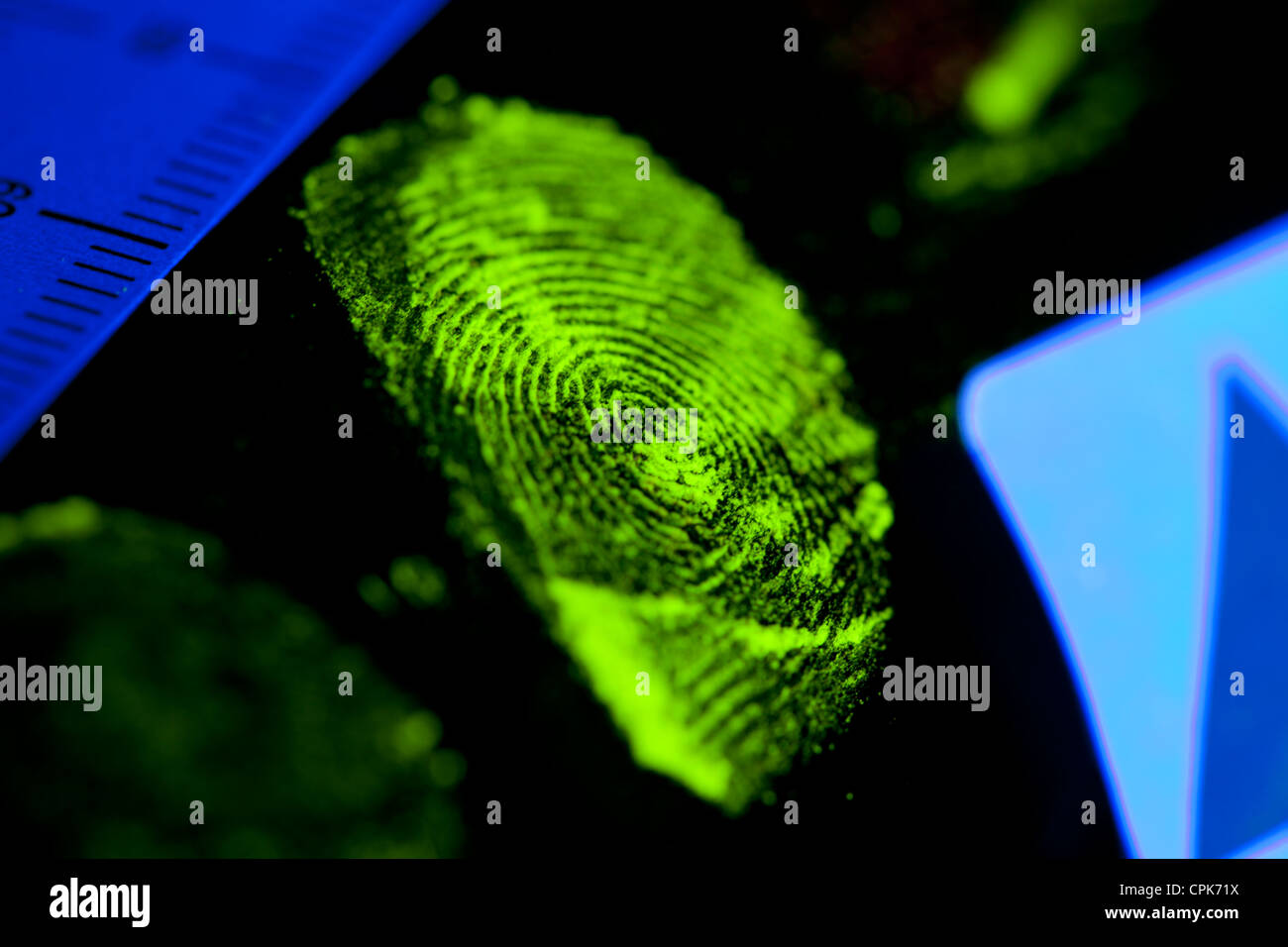 Tatort-Fingerabdruck auf Objekt, das mit ultraviolettem Staubpulver angereichert und unter ultravioletter Lichtquelle vom Kriminalermittler fotografiert wurde Stockfoto