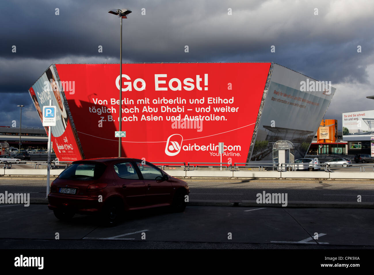 Dunkle Wolken drohen in einem hell erleuchteten Werbung für den stark verzögerten neuen Flughafen am alten Berlin Tegel (TXL). Stockfoto