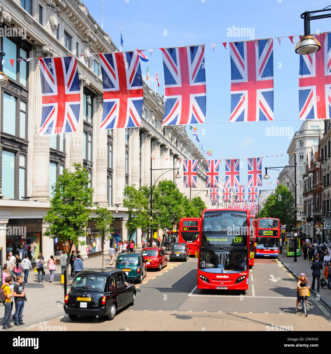 Schwarzes Taxi & Busse in der Oxford Street außerhalb Selfridges mit Jubilee Union Jacks, die auch während der Olympischen Spiele 2012 sein kann Stockfoto