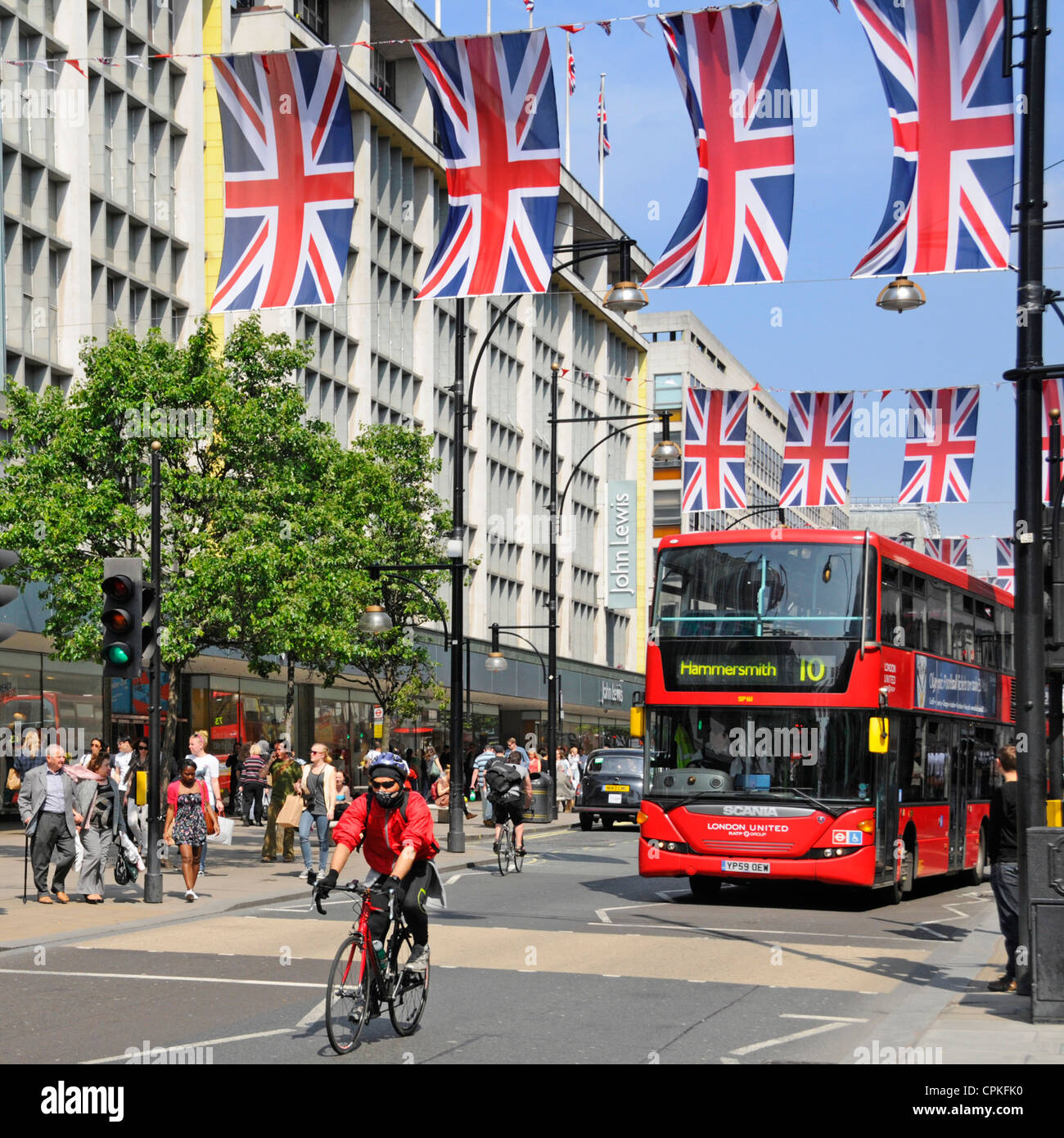 Roter Bus und Radfahrer tragen Mundschutz in der Oxford Street mit Jubilee Union Jacks, die auch während der Olympischen Spiele 2012 sein kann Stockfoto