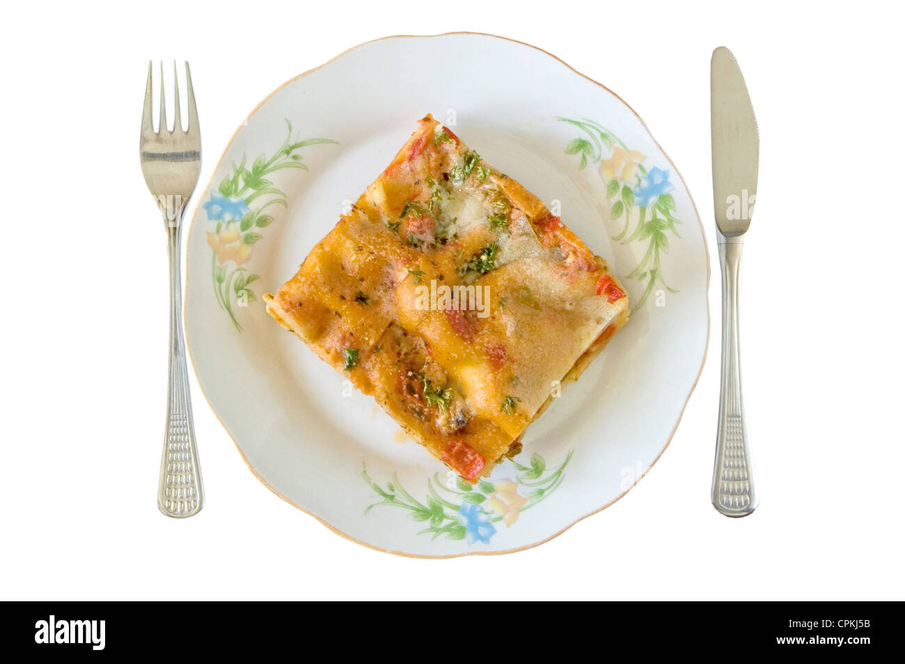 Lasagne-Slice in einem Teller mit Gabel und Messer isoliert auf weiss Stockfoto