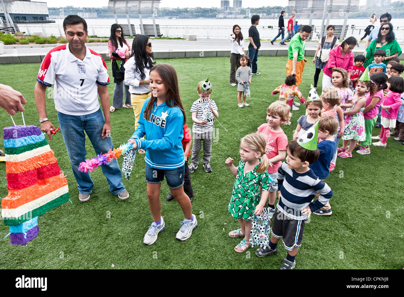 ältere Mädchen zeigt Sie mit der Wimper Regenbogen farbige 4 Ziel als Linie 4 Jahr Olds warten ihrerseits in Multi-ethnischen Geburtstags-party Stockfoto