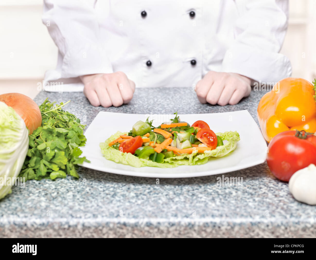 Salat auf Teller vor einem Koch Stockfoto