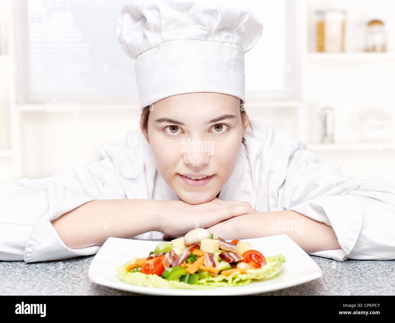 ziemlich Jungkoch und hers Teller mit einen leckeren Salat in Küche Stockfoto