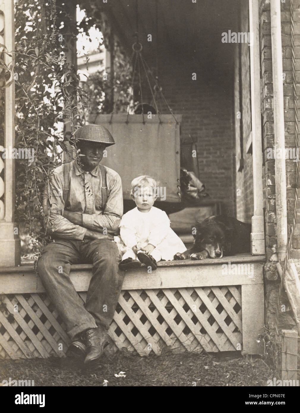 Vater, Kind Kind & Hund auf einer Veranda Stockfoto