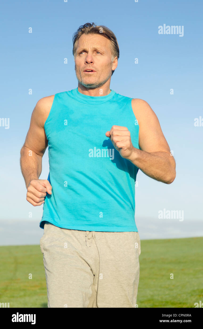 Ein Mann in einem Feld trägt einen blauen Tank Top zum Joggen. Stockfoto