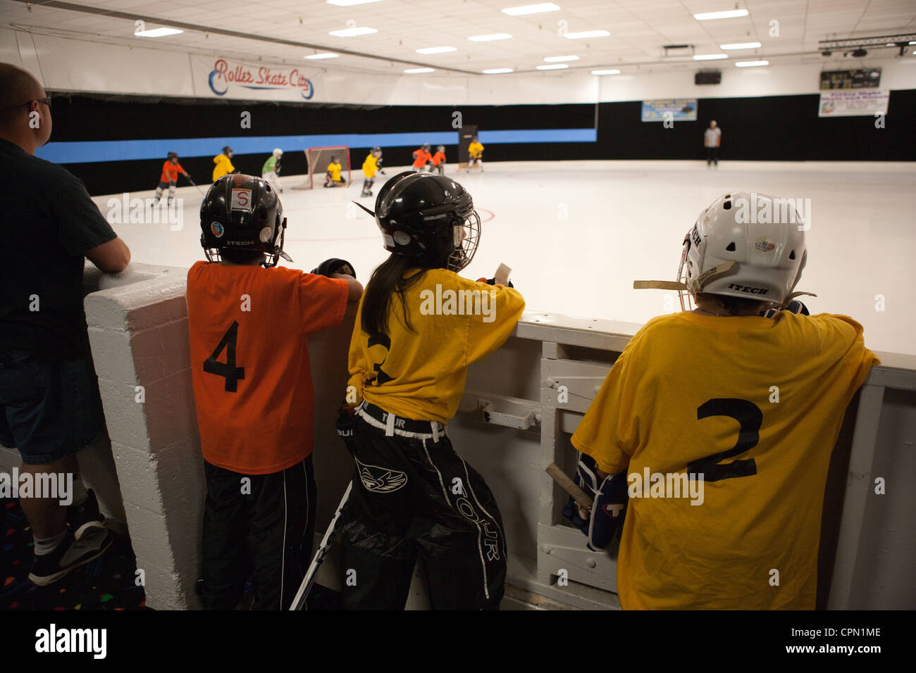 Acht Jahre alten Kinder einem Eishockey-Spiel beobachten und warten ihrerseits zu spielen. Stockfoto