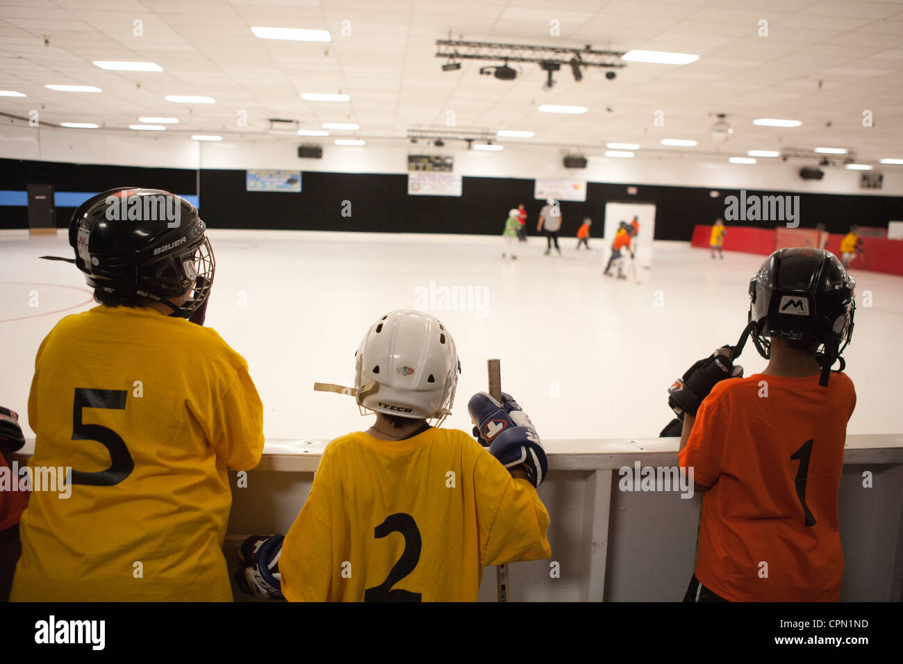 Junge Hockeyspieler beobachten Teamkollegen auf der Eisbahn. Stockfoto