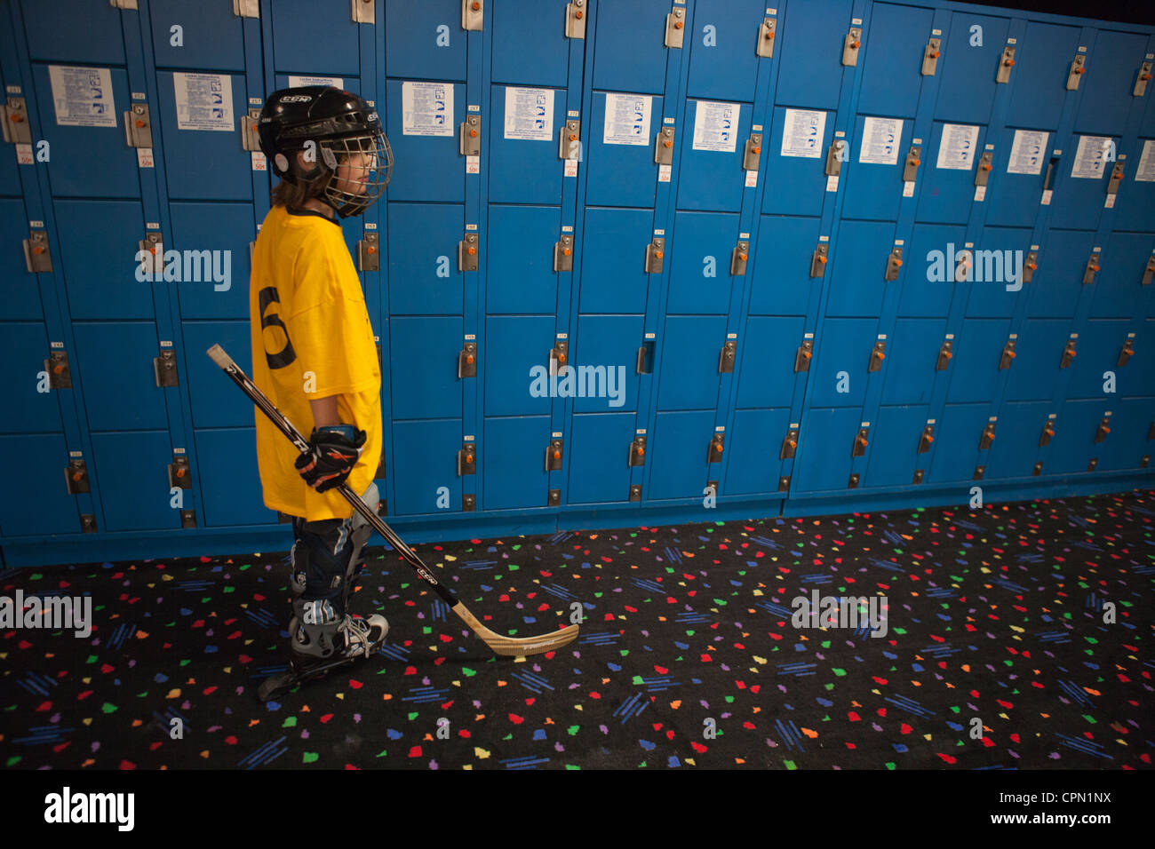 Neun Jahre alten Jungen für Rollhockey stehen vor einer Wand blaue Schließfächer gekleidet. Stockfoto