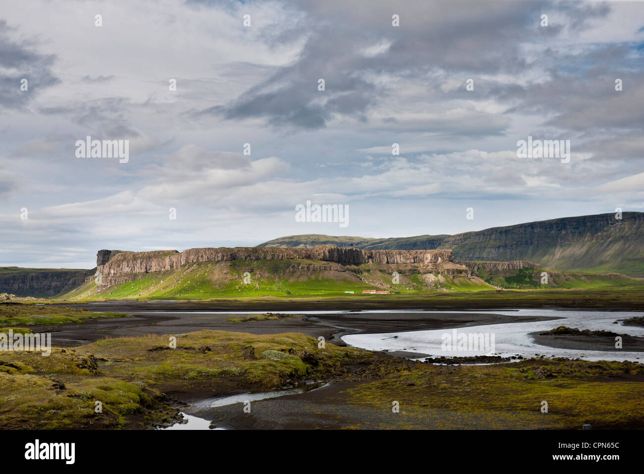 Island, Bach durch Lavafeld, Basaltfelsen in der Ferne Stockfoto