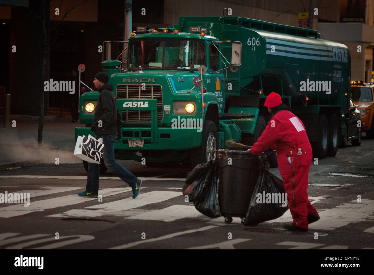 New Yorker Times Square Street Reiniger arbeitet infront von einem grünen Mack Lkw Tanker einen Zebrastreifen überqueren Stockfoto
