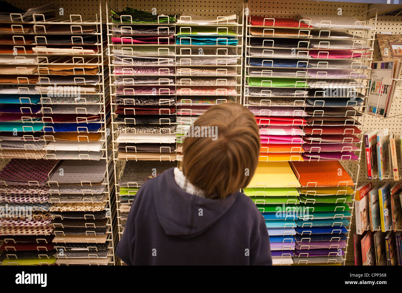 Neun Jahre alten Jungen versuchen zu entscheiden, welche Farbenpapier braucht er für Kunstprojekt im Ladengeschäft. Stockfoto