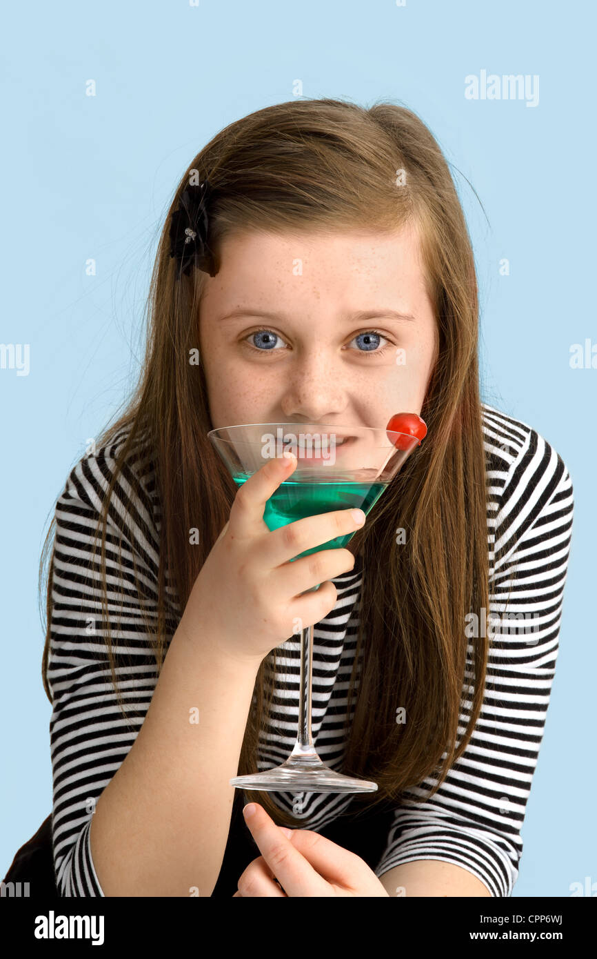 Ein neun Jahre altes Mädchen, trinken einen Cocktail mit Kirsche. Alkoholkonsum Stockfoto