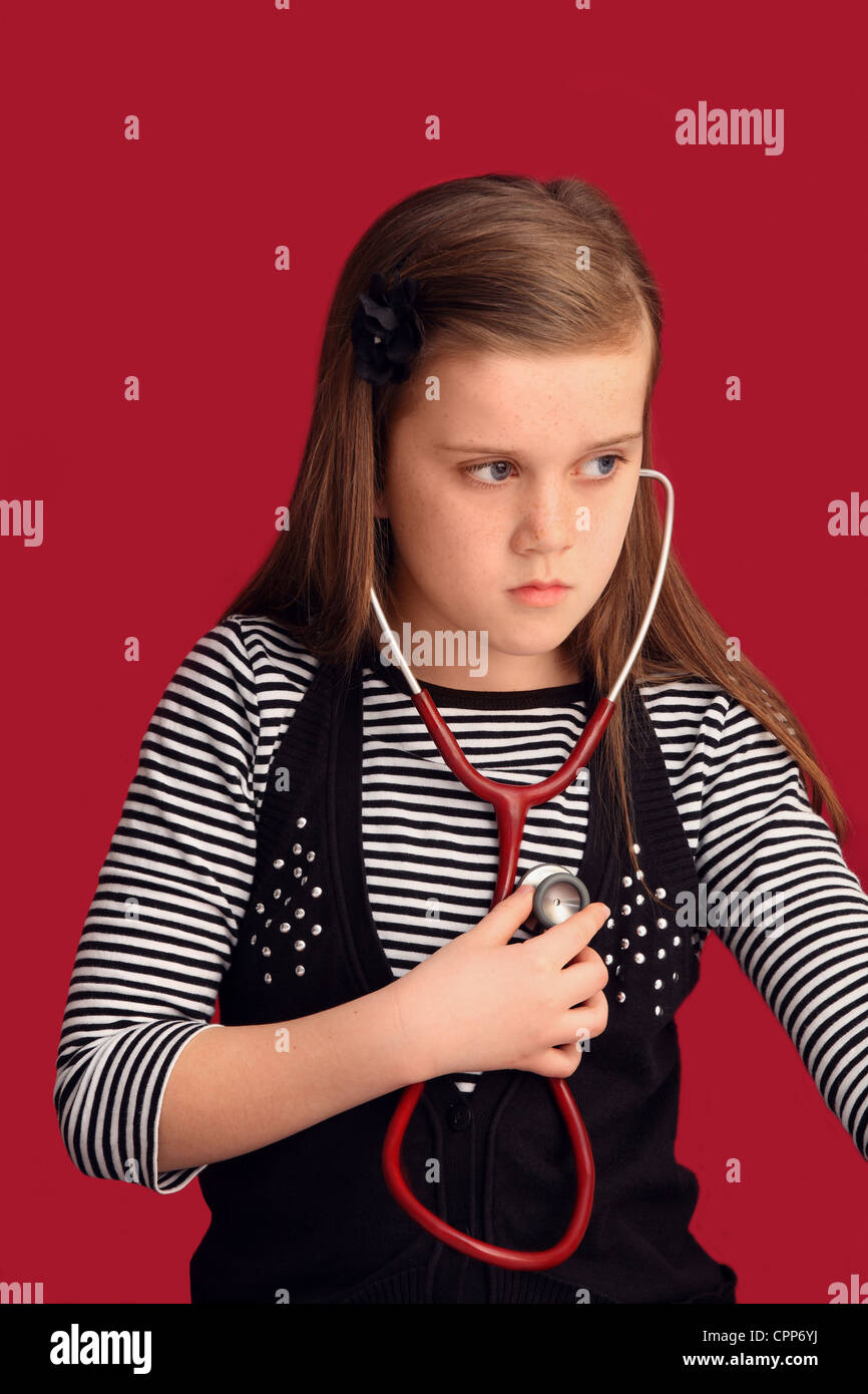 Ein neun Jahres altes Mädchen hört ihr Herz durch ein Stethoskop Stockfoto