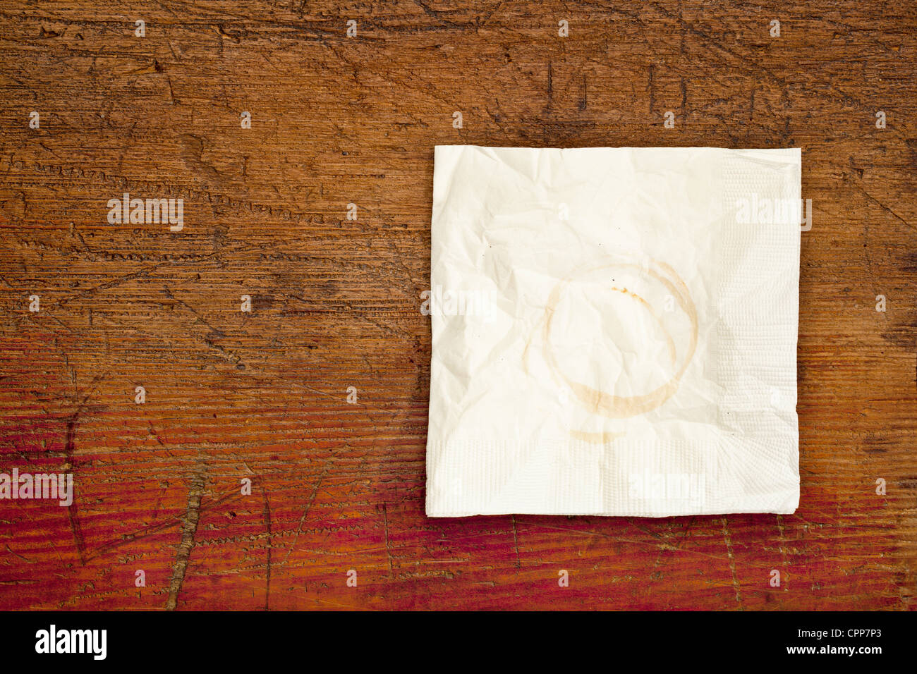 Serviette mit Kaffeeflecken auf einem verkratzten Holztisch grunge Stockfoto