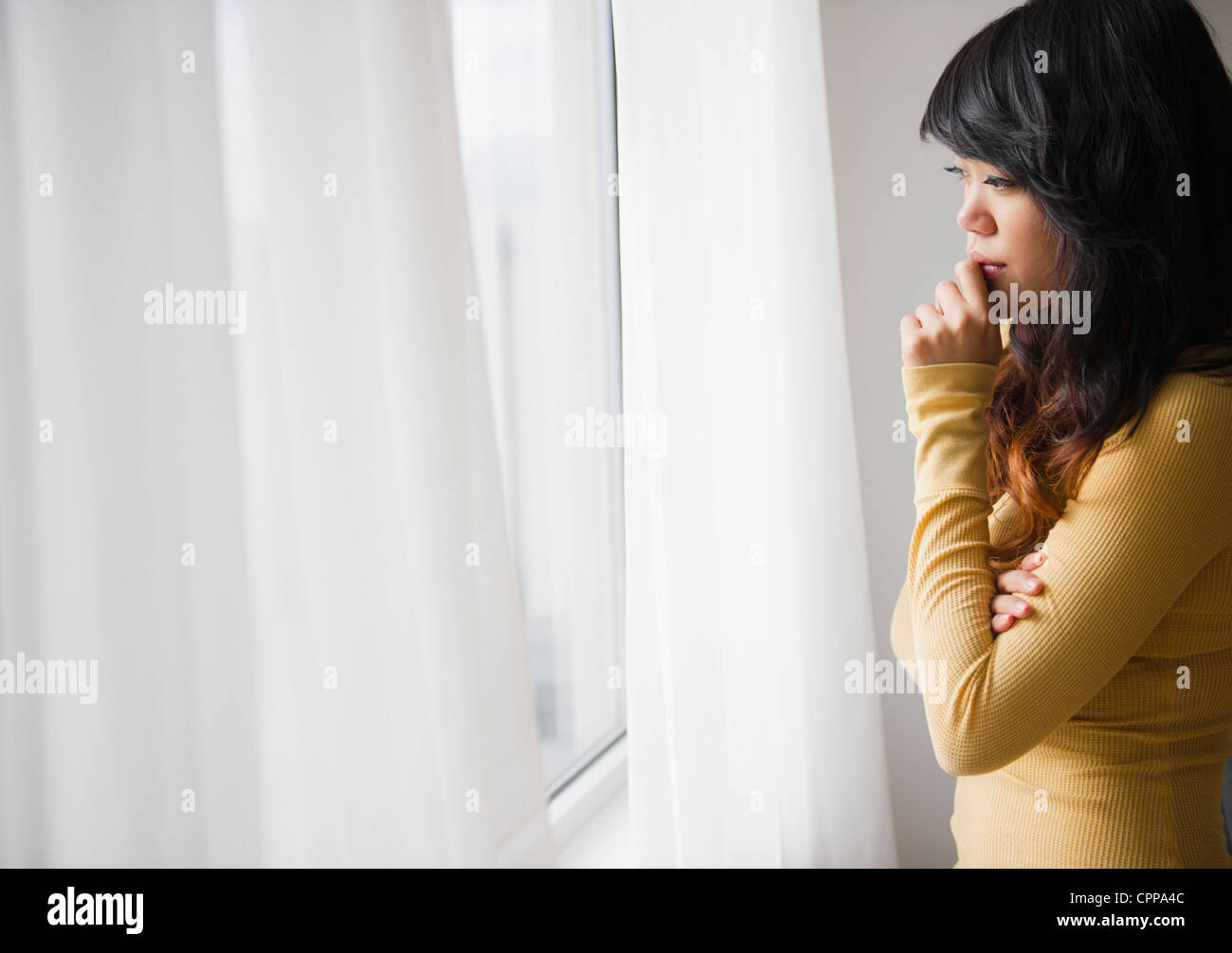 Pacific Islander Frau schaut aus Fenster Stockfoto