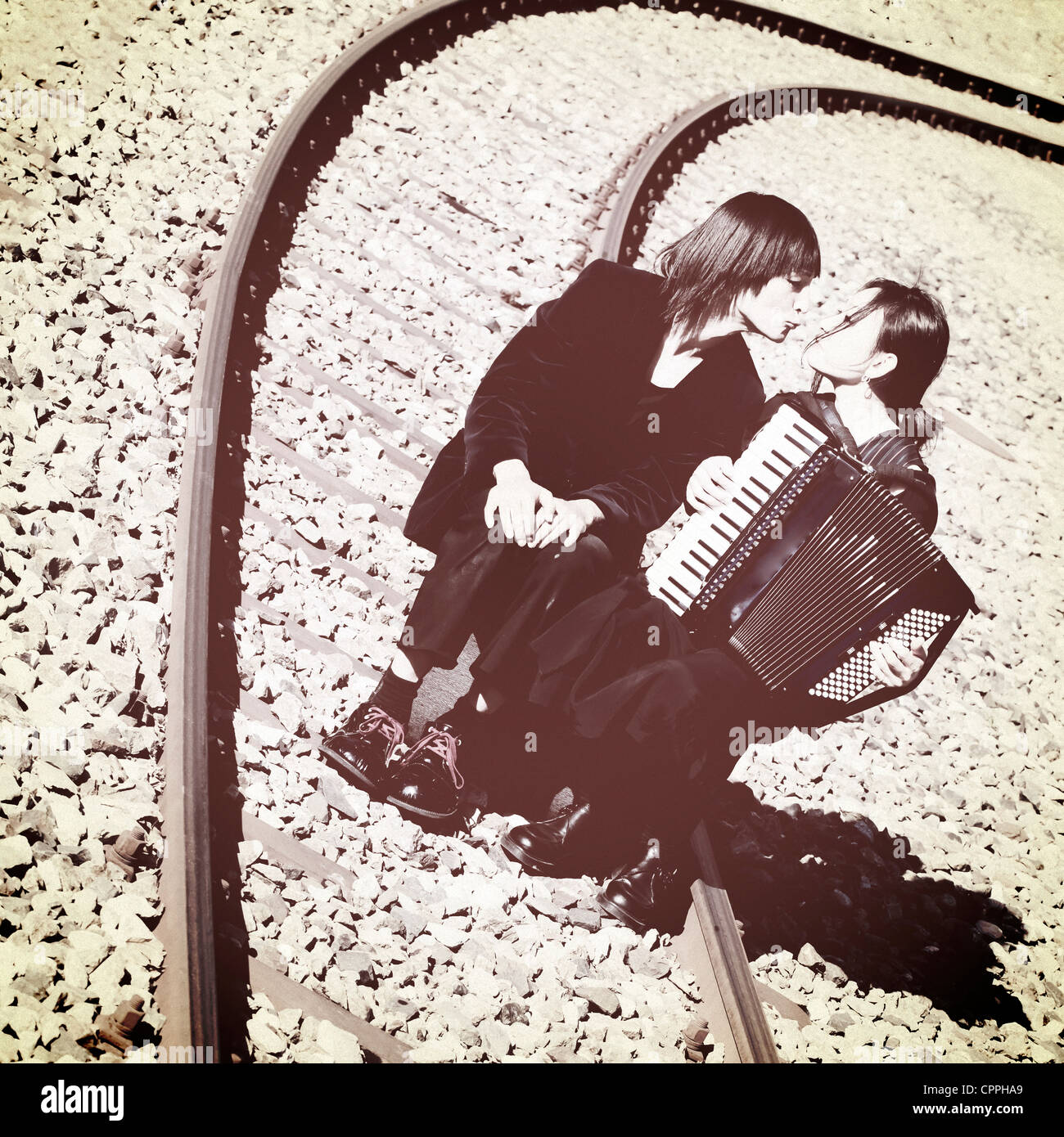 ein Vagabund paar sitzt auf Eisenbahnschienen und Küsse Stockfoto