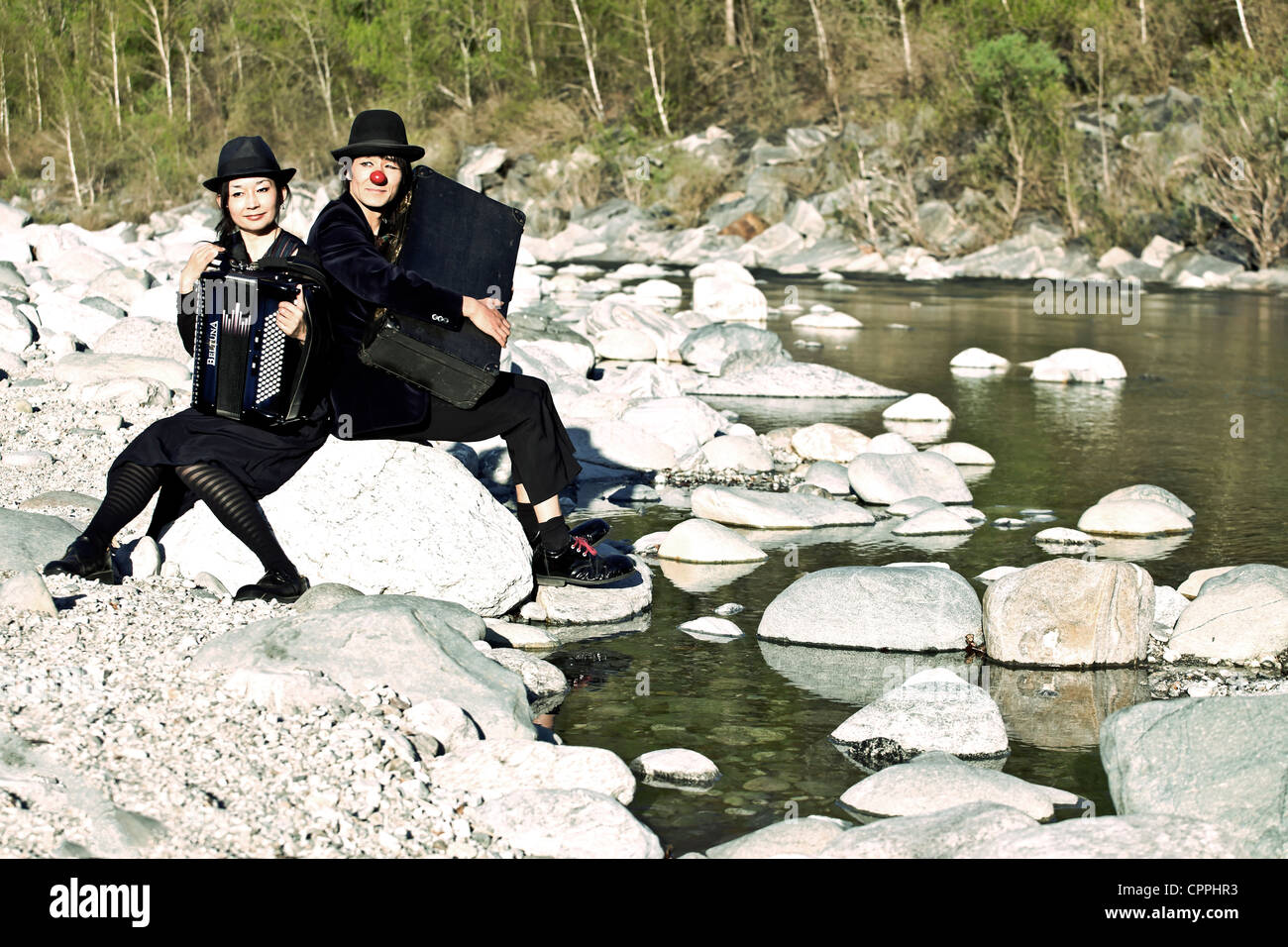 ein Clown paar sitzt auf einem Felsen am Ufer eines Flusses Stockfoto