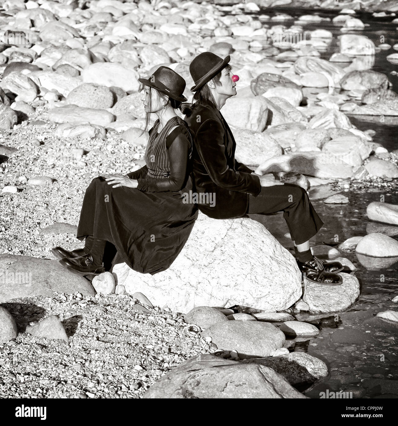 ein Clown paar sitzt auf einem Felsen am Ufer eines Flusses Stockfoto
