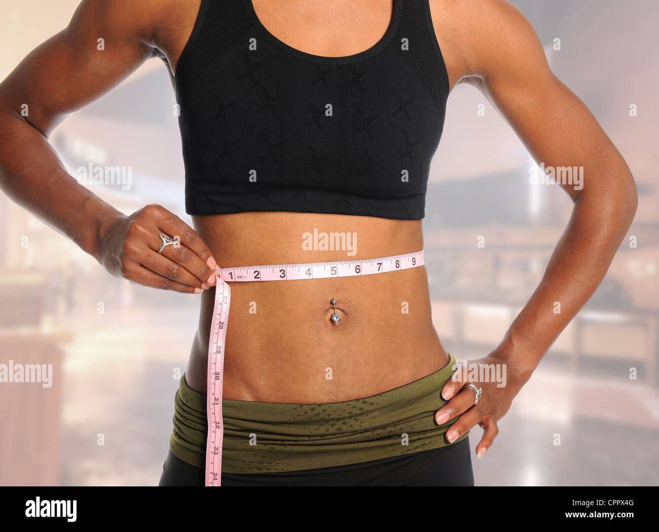 Muskulöse junge Frau messen Taille mit Klebeband über unscharfen Hintergrund isoliert Stockfoto