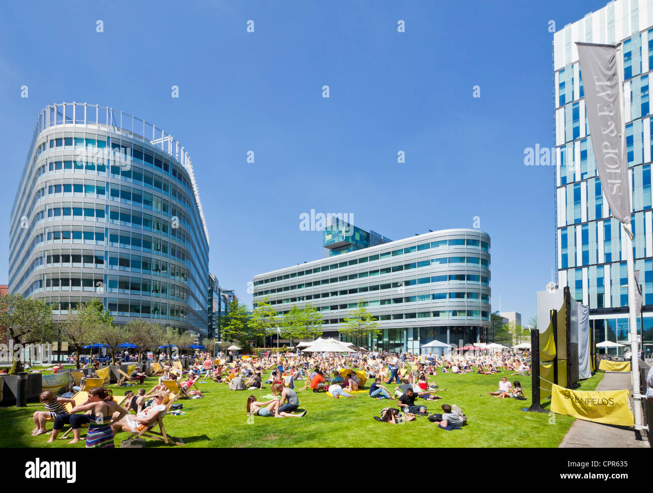 Menschenmassen genießen das warme Wetter und Sonnenschein in der Stadt Zentrum Spinningfields größere Manchester England UK GB EU Europa Stockfoto