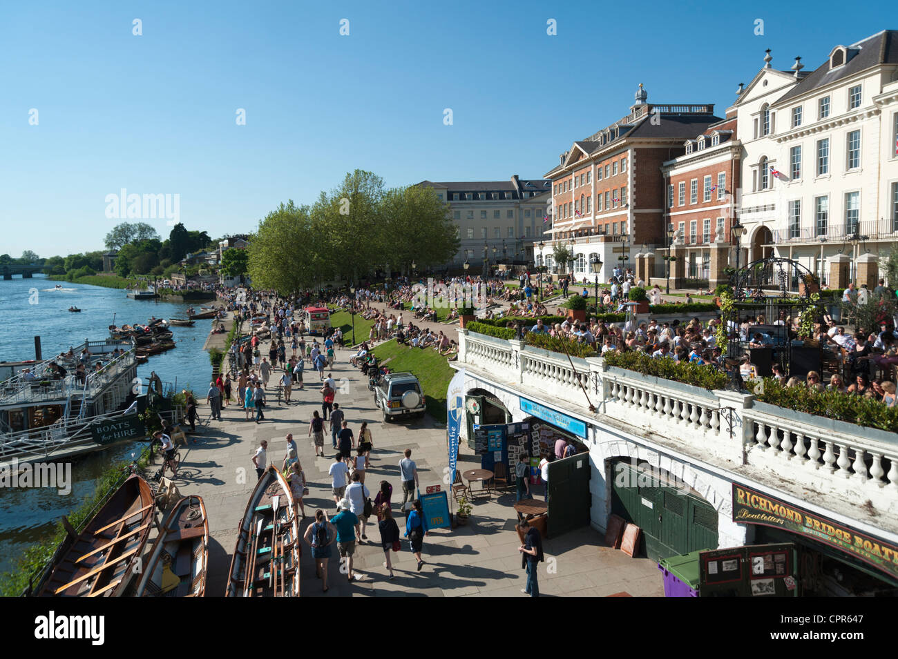 Die Riverside walk entlang dem Fluss Themse Richmond London an einem sonnigen Tag mit Massen von Menschen sitzen auf dem Rasen im Sommer. Stockfoto