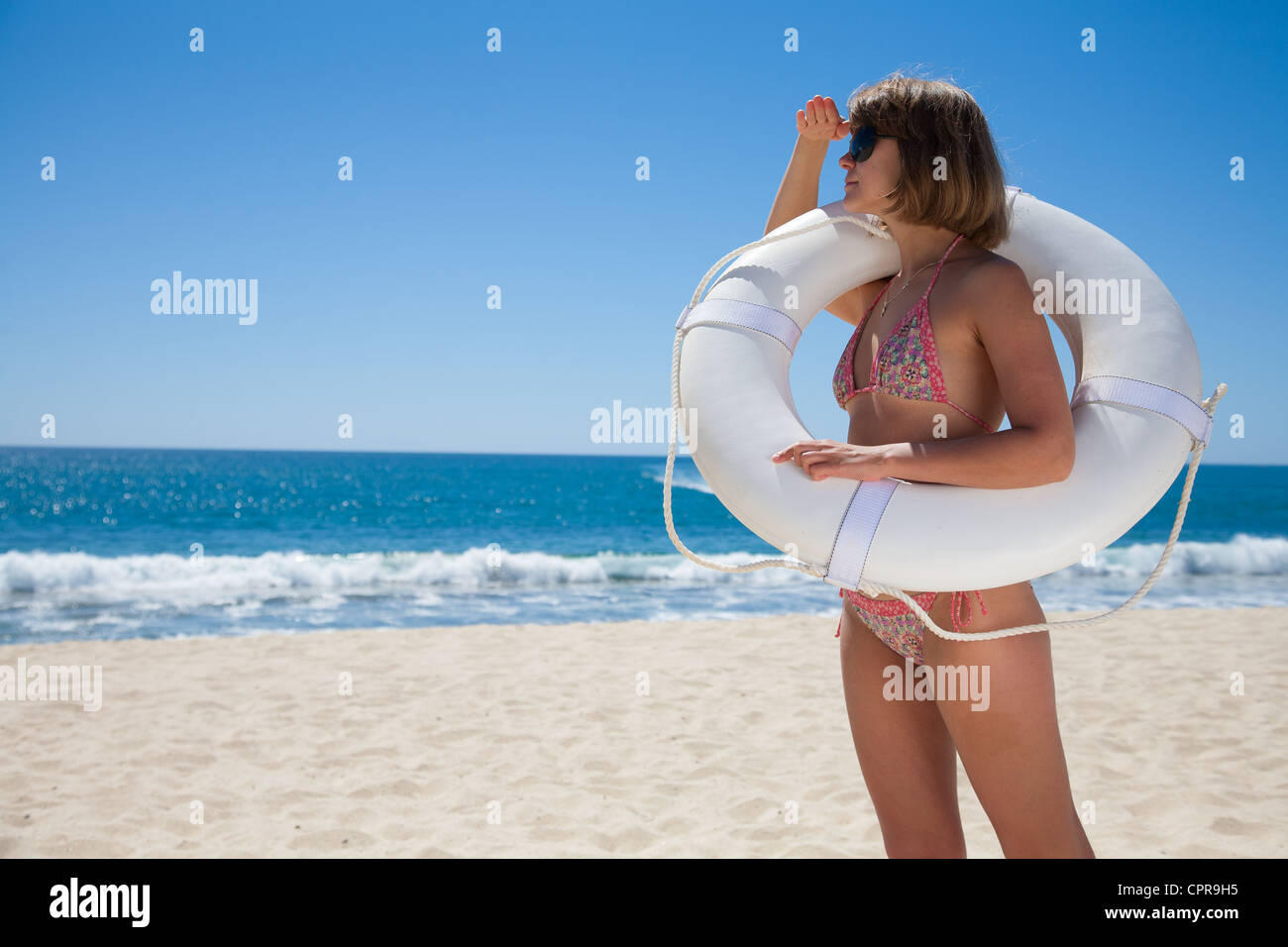 Junge Frau, die gerade der Bucht mit einem weißen Rettungsring Stockfoto
